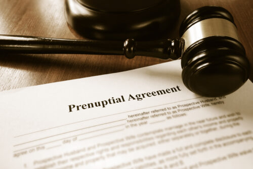 A close-up of a prenuptial agreement document on a desk, with a wooden judge’s gavel and sound block nearby, highlighting legal matters like prenuptial agreements and child custody.